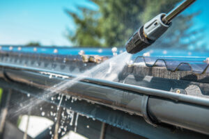 A professional cleaning gutters with a pressure washer