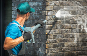 a professional pressure washing a brick wall